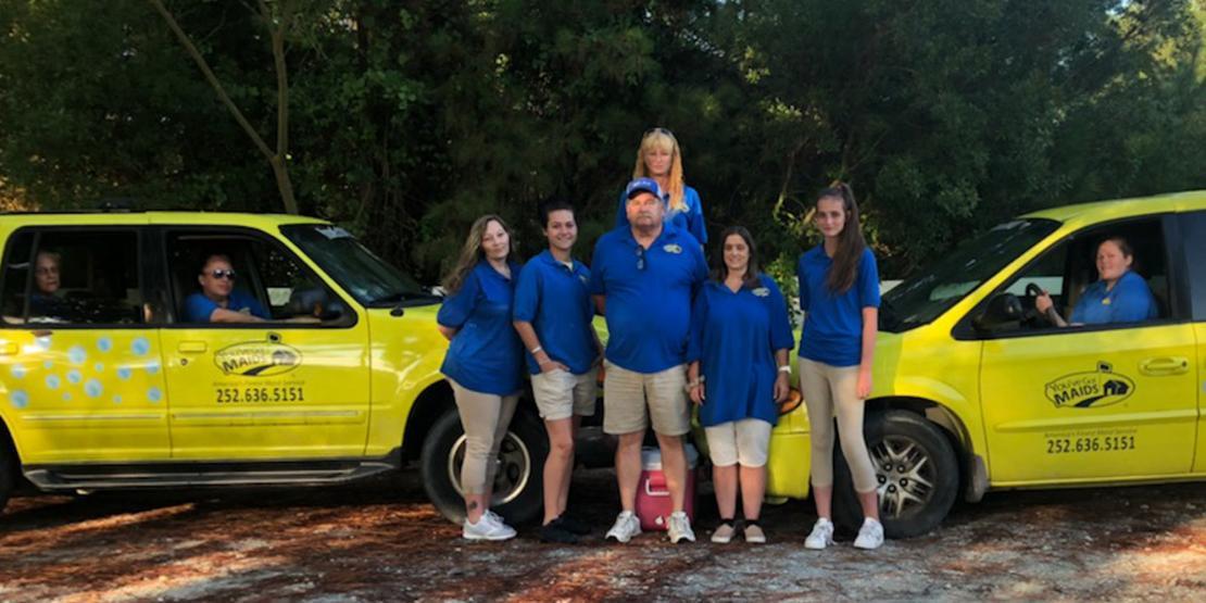 Phil and Jill Vernelson (center), owners of You’ve Got Maids, and members of their team are pictured with replacement vehicles after previous ones were flooded in Hurricane Florence.