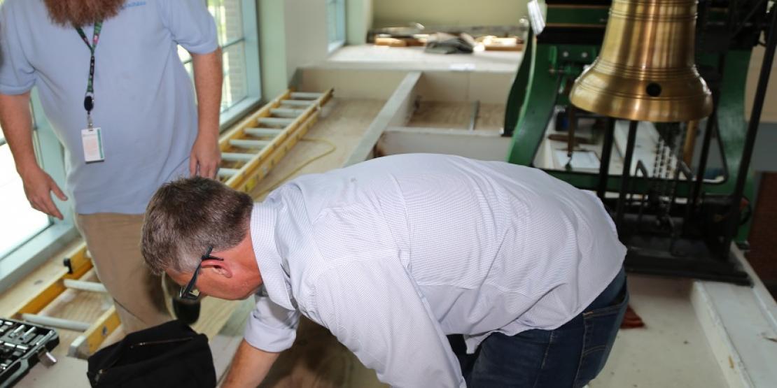 Tryon Palace Network & Exhibits System Administrator Rob Jones (left) and Craven CC instructor Jeff Brown replace a broken piece of a 1911 mechanical clock, located in the North Carolina History Center.