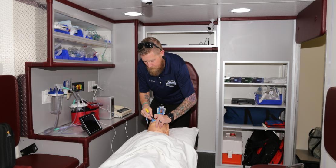 Jon Stephens, Craven CC EMS program coordinator and instructor, demonstrates placing a king airway in a patient simulator inside the college’s new ambulance simulator.