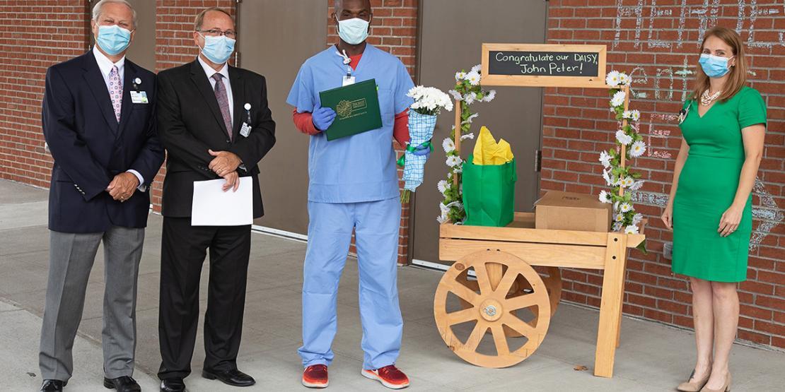 CarolinaEast Health System officials present John Peter, former Craven CC nursing student, with a DAISY Award for outstanding service. Pictured left to right: Ray Leggett, President/CEO of CarolinaEast Health System; Jim Davis, Chief Nursing Officer and Vice President of Nursing; John Peter, ER nurse; and Becky Skinner, BSN, RN, PCCN and Professional Development Specialist.