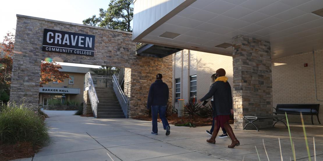 three students walking by New Bern campus entrance