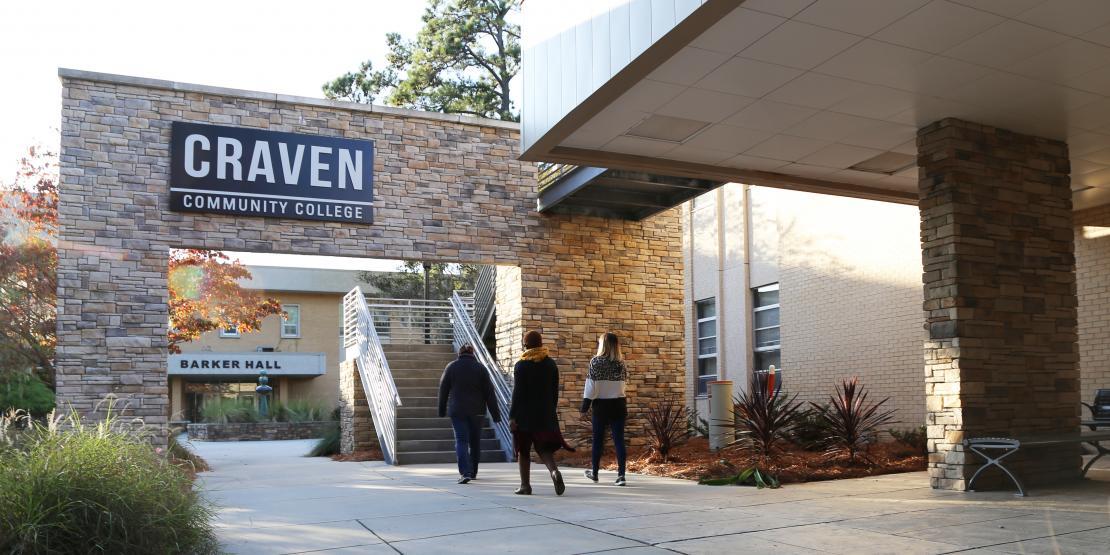 Students walking outside under exterior sign