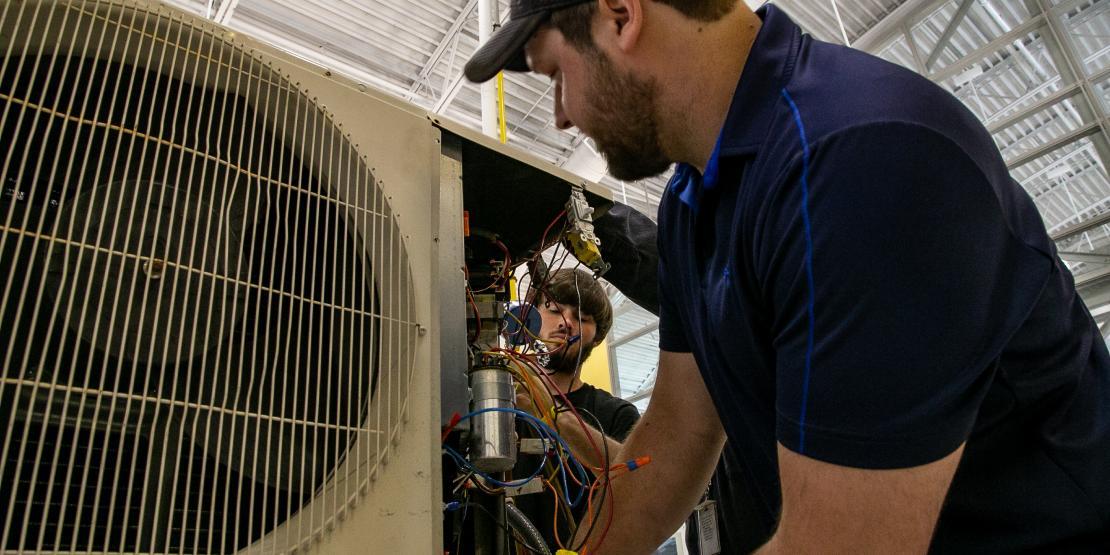 HVAC students work on an air conditioning unit