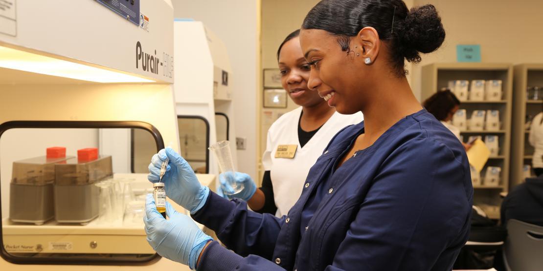 Pharmacy technician student practices extracting medication in a syringe