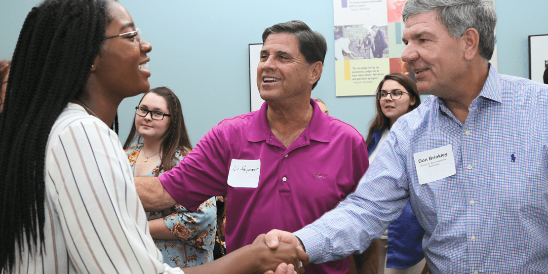 Student and scholarship recipient shakes hands with Foundation members