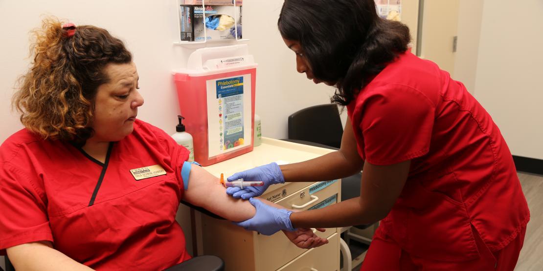 Phlebotomy student drawing blood from instructor