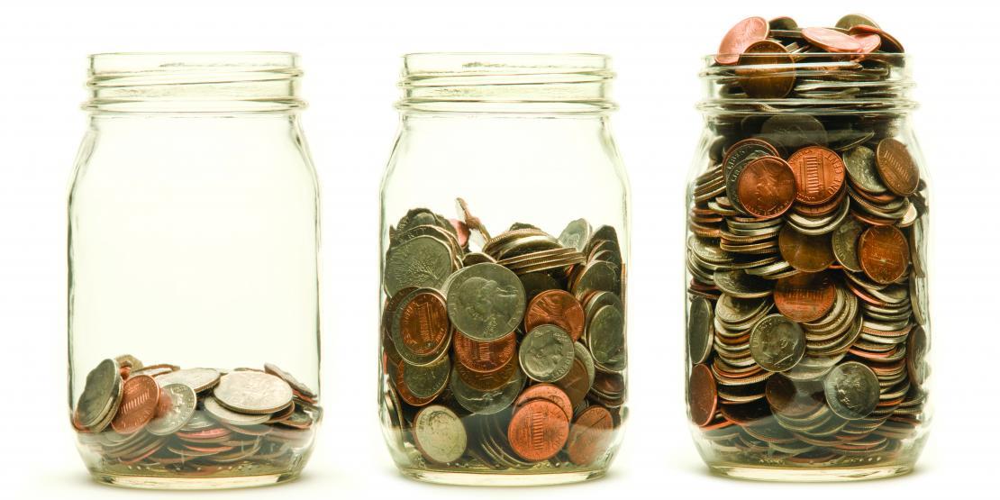 Three glass jars increasingly filled with coins