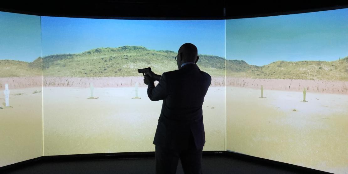 Man pointing firearm in front of projection screen