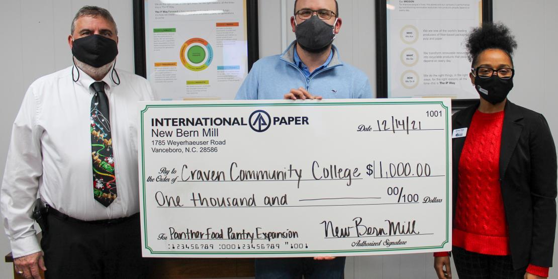 Craven CC Executive Director of Institutional Advancement Charles Wethington (left) and Dean of Student Services Zomar Peter (right) accept International Paper's donation to the college's Panther Pantry from Adam Miklos, mill manager, New Bern mill.