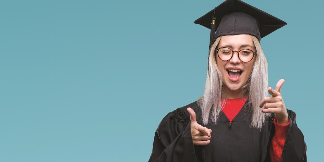 Happy female graduate pointing and winking at camera