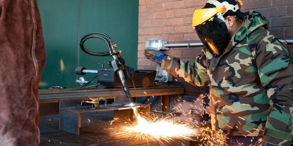 Two welding students practice welding outside