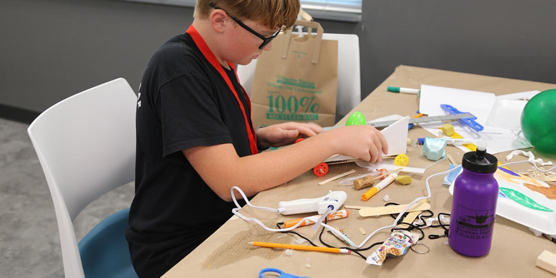 Boy using hot glue gun on craft