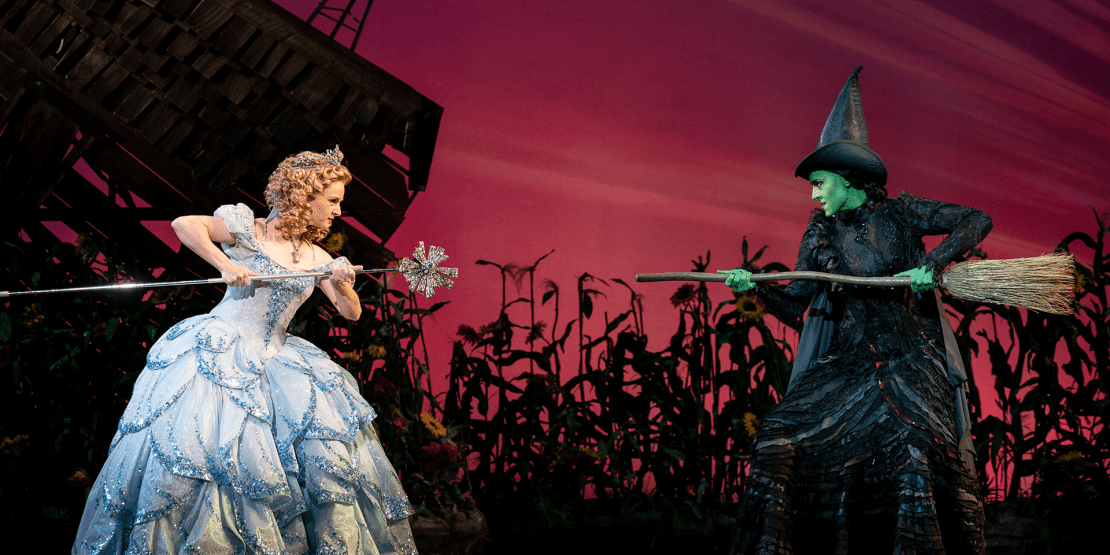 Broadway show Wicked with Glenda the Good Witch with a wand battling the Wicked Witch of the West with a broom