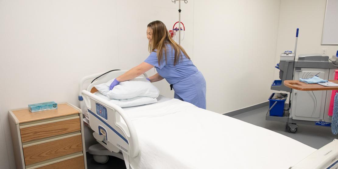 Meghan Margarum practices environmental services and housekeeping tasks in a hospital room.