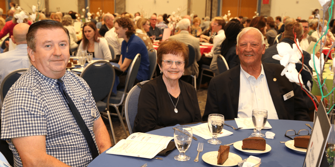 Three attendees at a table for the Community Fabric Awards event in April 2023