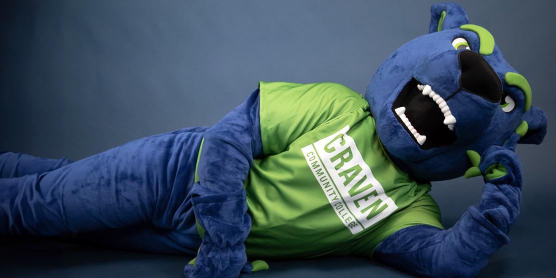 Blaze the blue panther mascot wearing a green Craven Community College T-shirt