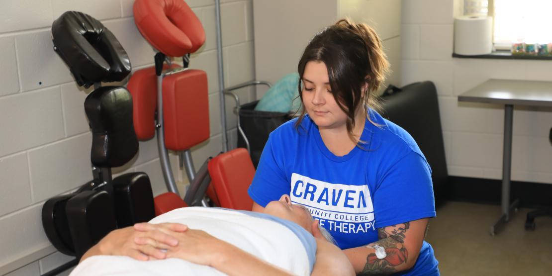 Female massage therapy student practices techniques on another female student