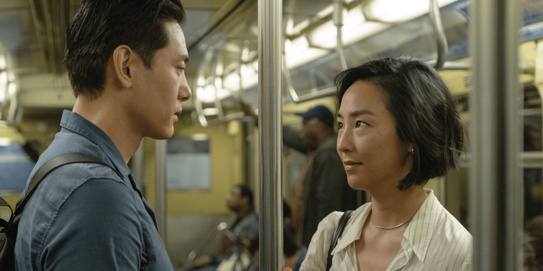 Asian male and female looking at each other intently while riding on a train