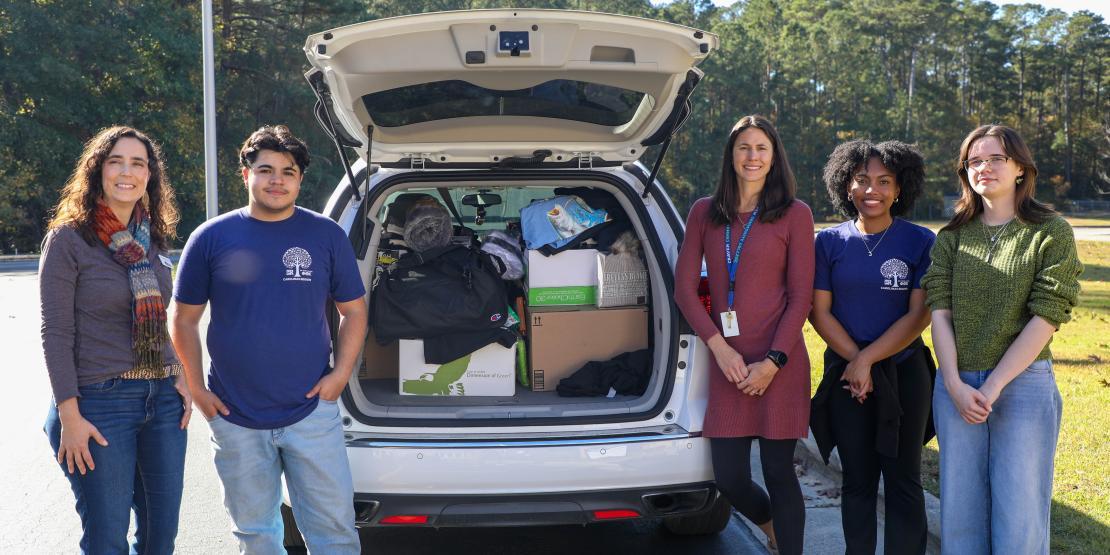 Students and advisors of Craven's Phi Theta Kappa chapter load donations into a car trunk.