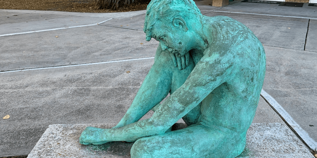 Bronze statue of life-sized nude male on a bench