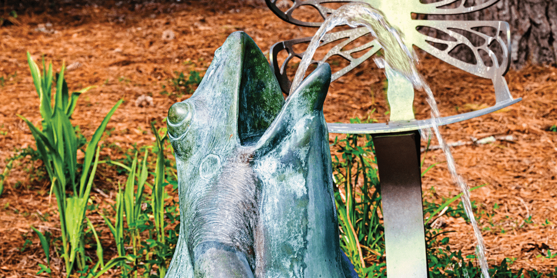 Bronze frog fountain statue spewing water out of its mouth