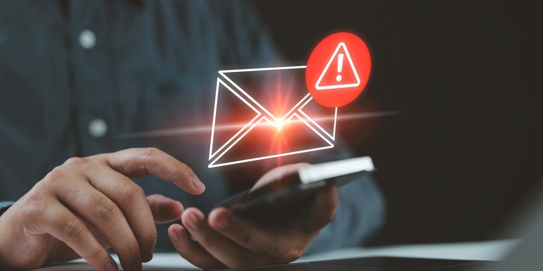 Close up of person holding a phone about to tap the screen, with an envelope and alert symbol above it