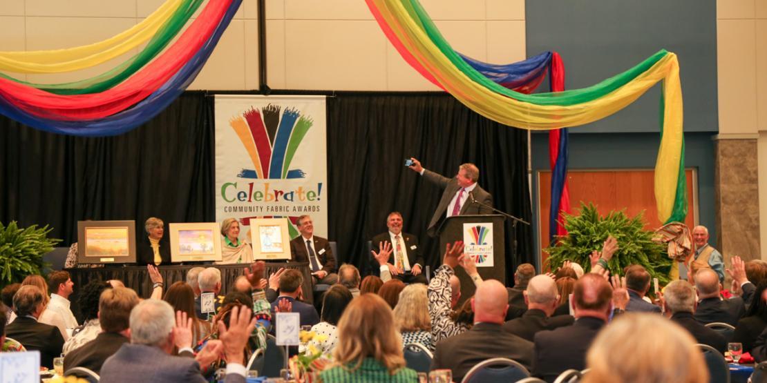 Emcee Brian North takes a selfie on stage during the 2024 Community Fabric Awards