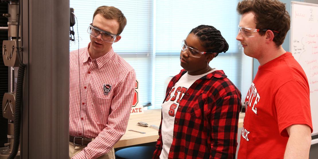 Male instructor teaches a female and male student about engineering