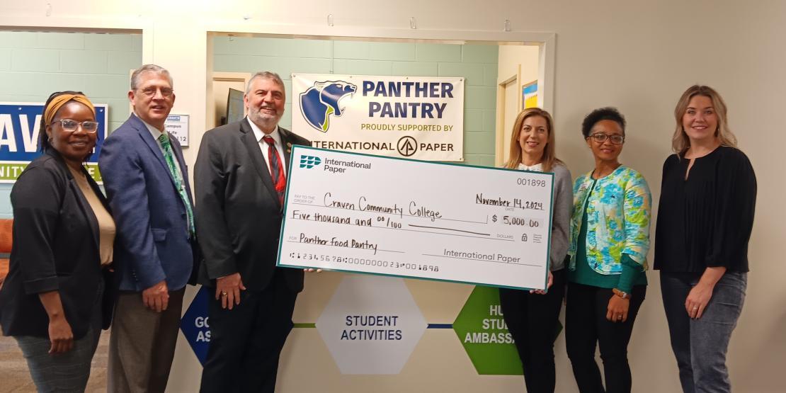 Craven and IP representatives hold a check for the Panther Pantry
