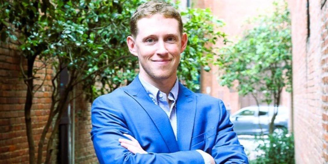 Craven alum Trevor Dunnell poses with arms crossed outside in downtown New Bern