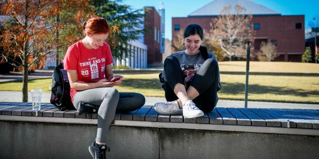 students sit outside on NC State Campus