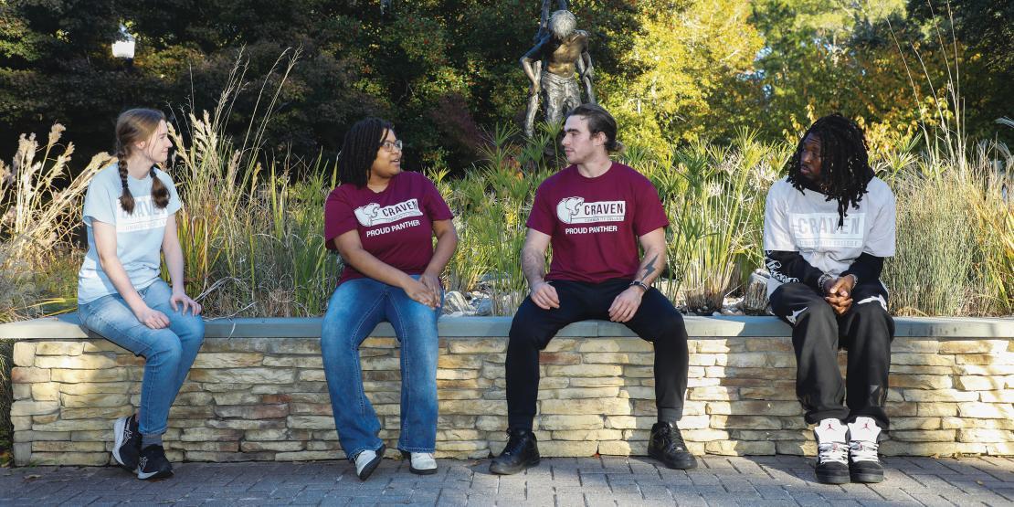Two female and two male student government association members sit outside talking