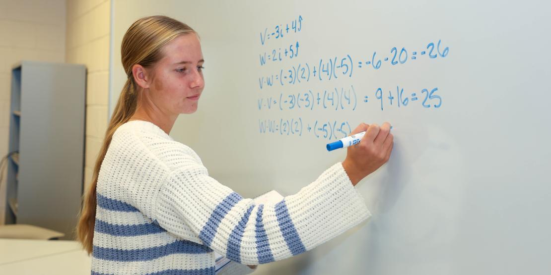 Student Sarah Fedyna writes math problem on whiteboard