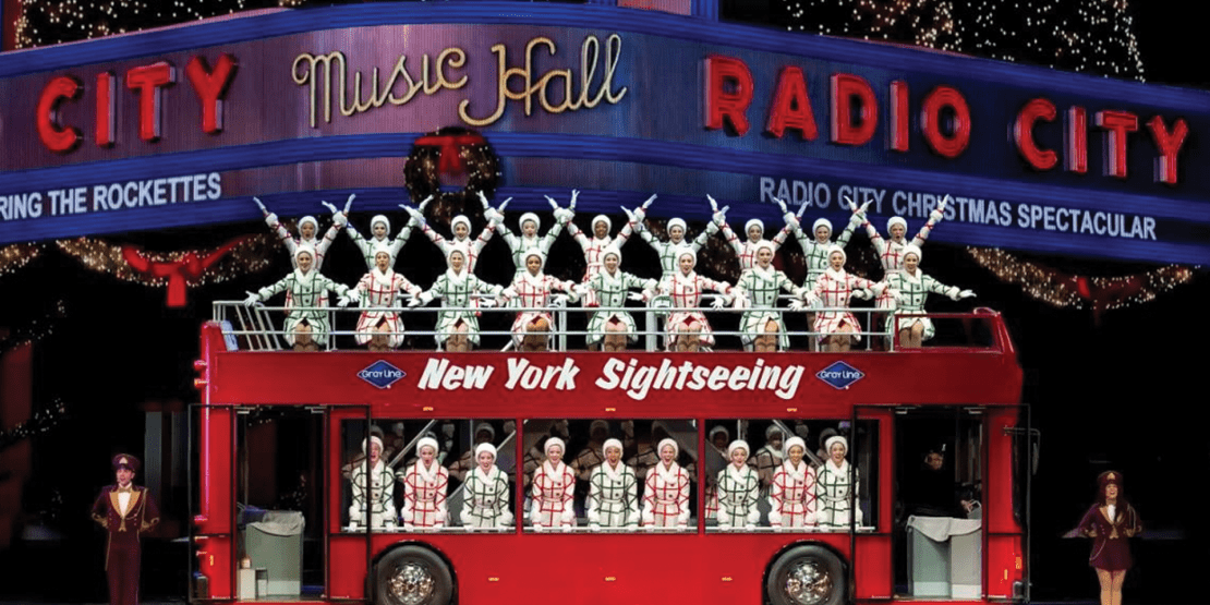 Dancers pose on a tour bus prop during a performance for NYC Rockettes Christmas Spectacular