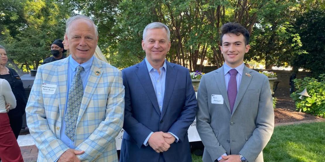 Three men stand together in suits