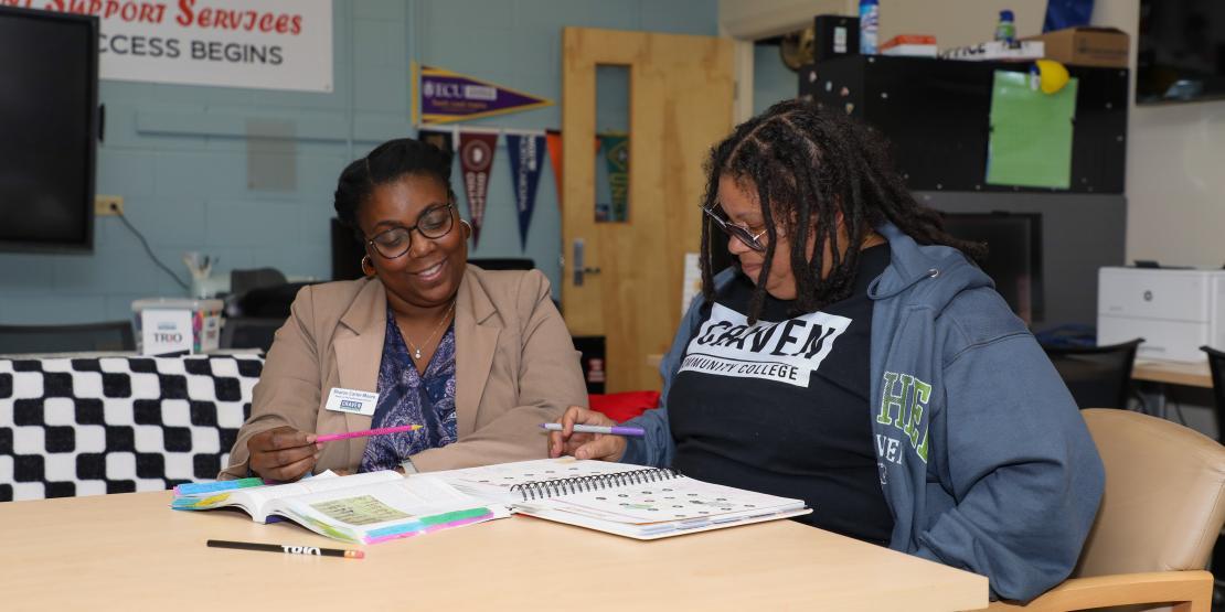 two women sit at table tutoring