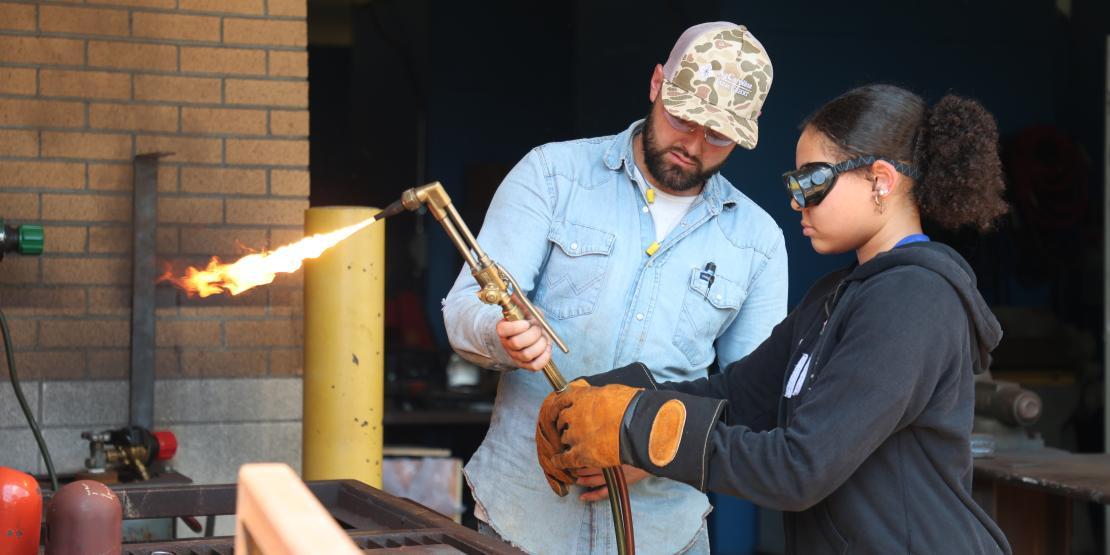 Instructor helps student with welding torch