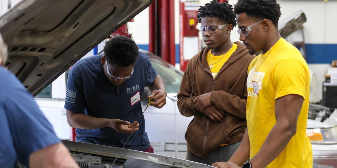 three men work under car hood