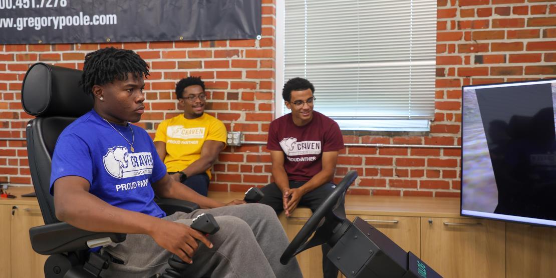 student sits at heavy equipment simulator