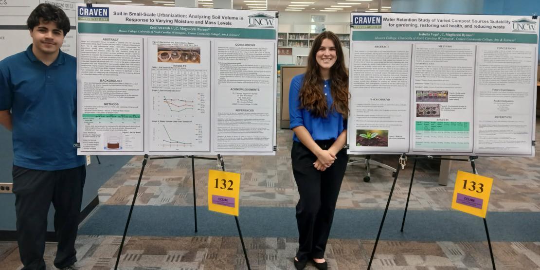Two students stand with poster projects