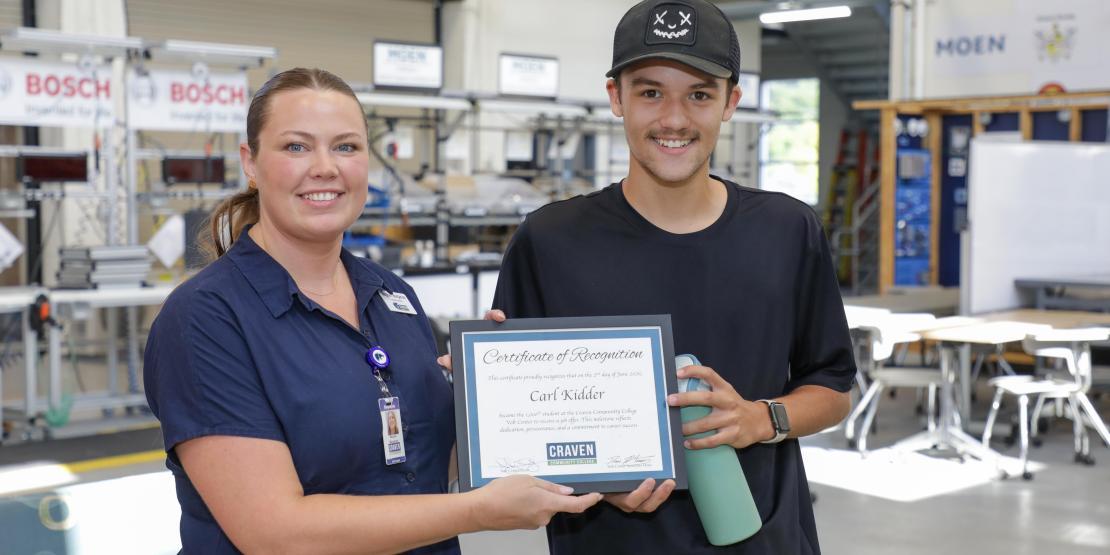Man and woman standing and holding a certificate. 