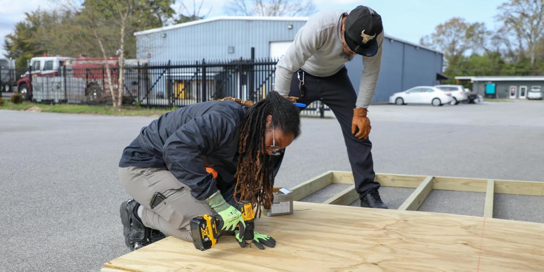 student drills into wooden platform