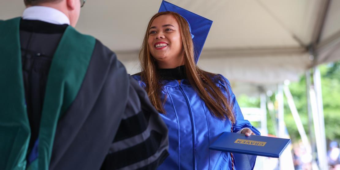 Smiling Craven Community College graduate receives their diploma during commencement.