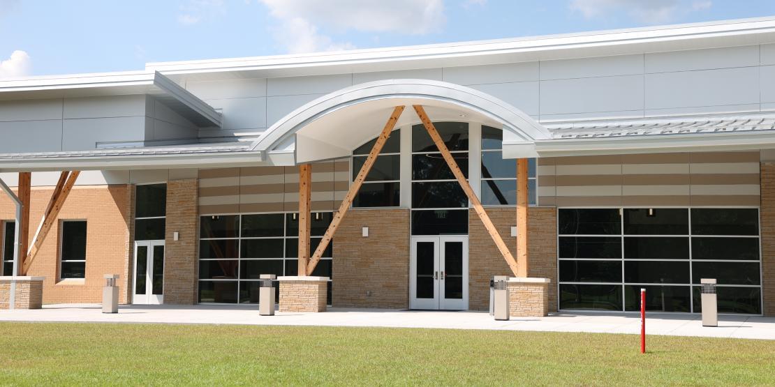 Front exterior of the Corporate Training Center, featuring a curved entrance canopy, large windows, and exposed wooden supports.