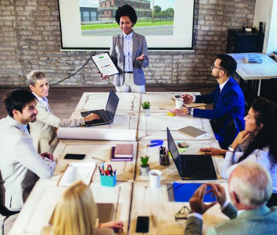 Woman gives business presentation in front of conference table of people