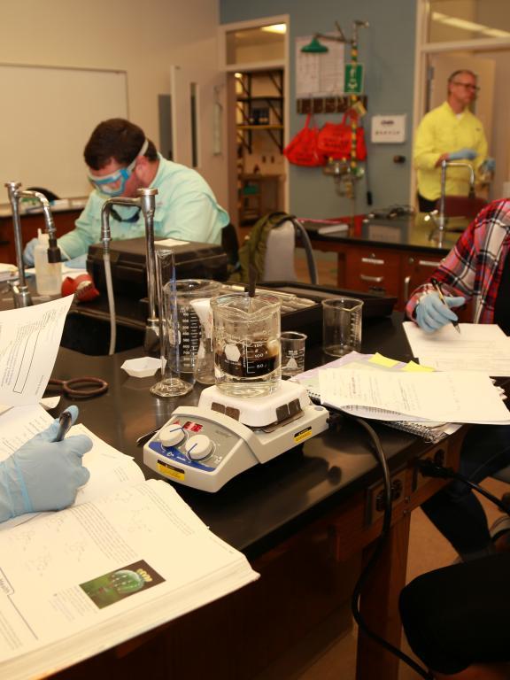 Group of chemistry students conduct experiment in classroom