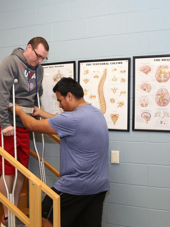Physical Therapist Assistance program student helps another student on crutches 
