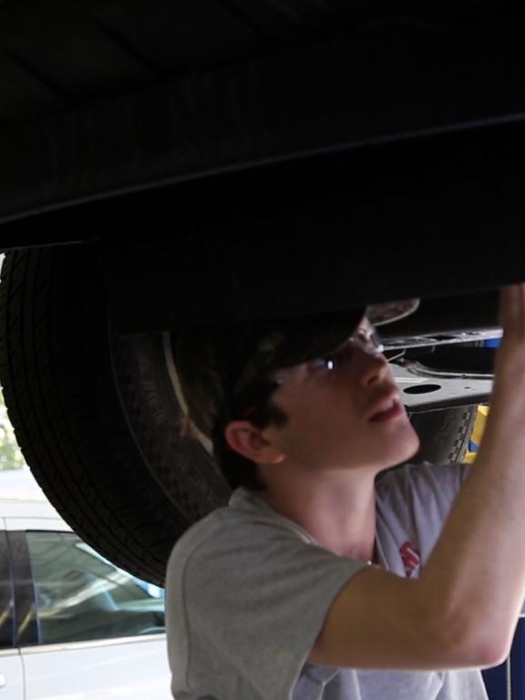 Automotive student working under lifted car