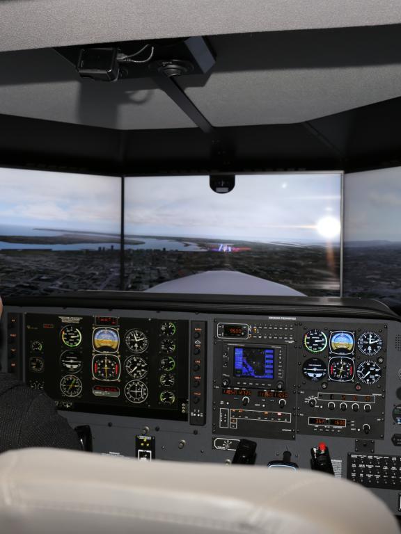 Female aviation student practices in flight simulator