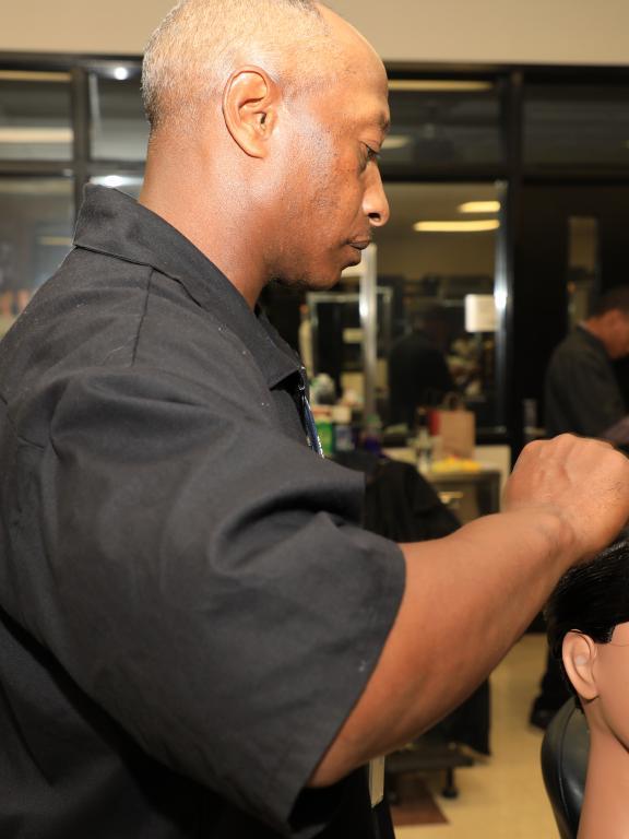Barbering student practices styling hair